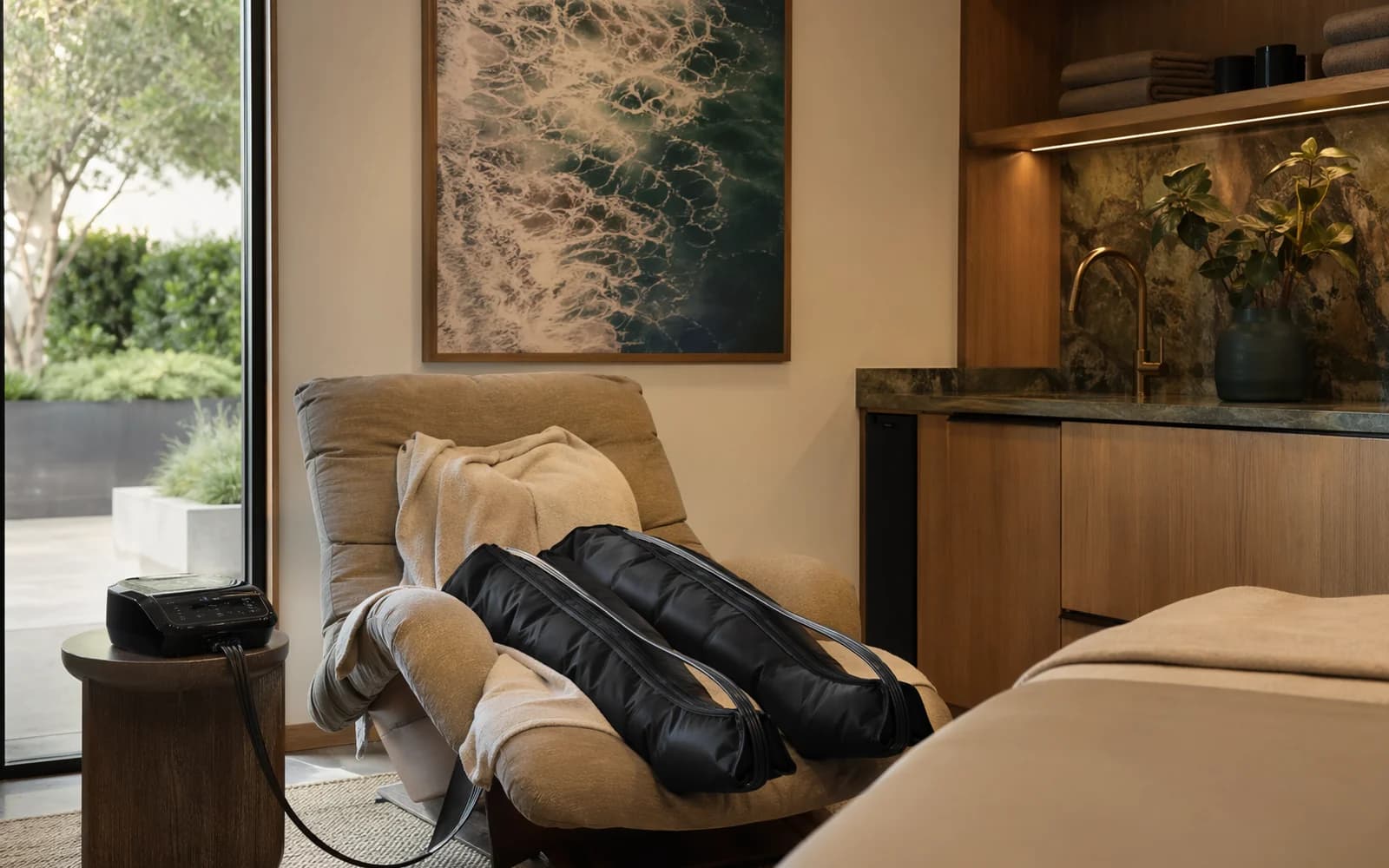 Compression boots beside a lounge chair in a recovery setting.