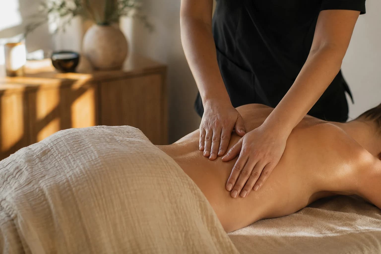 Personalized massage therapy with hands-on back work in a warm treatment room.