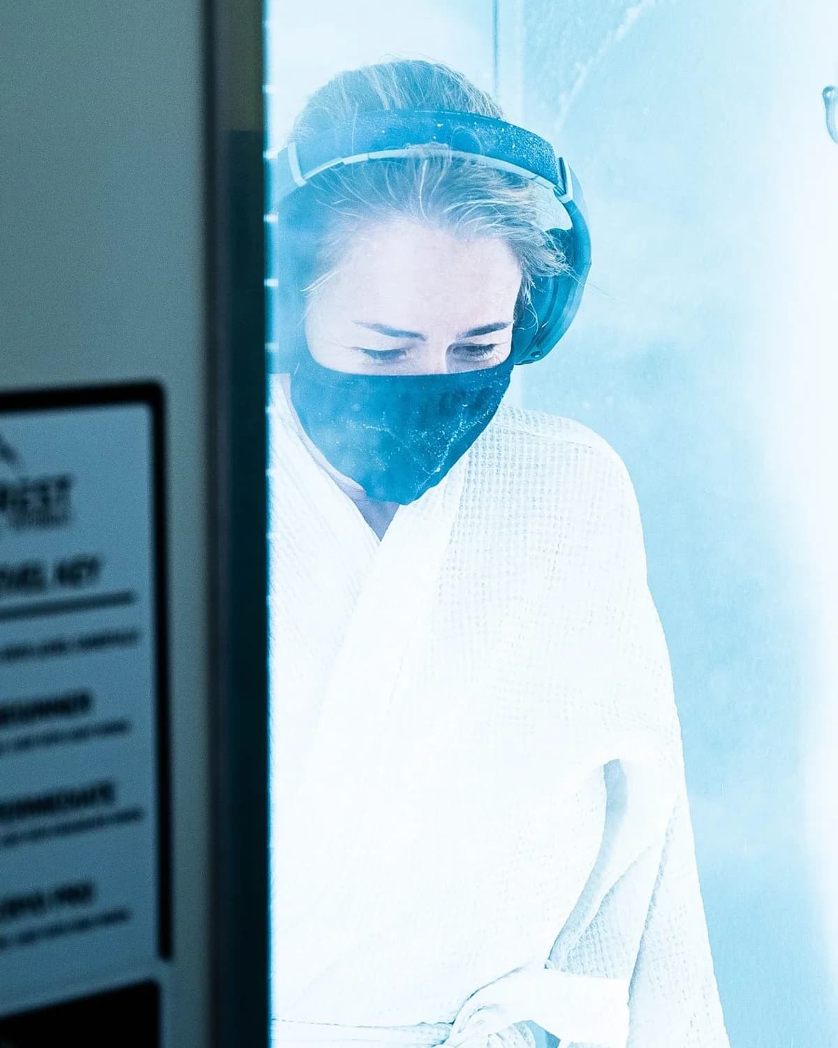 Whole-body cryotherapy client in a bright cold recovery chamber.