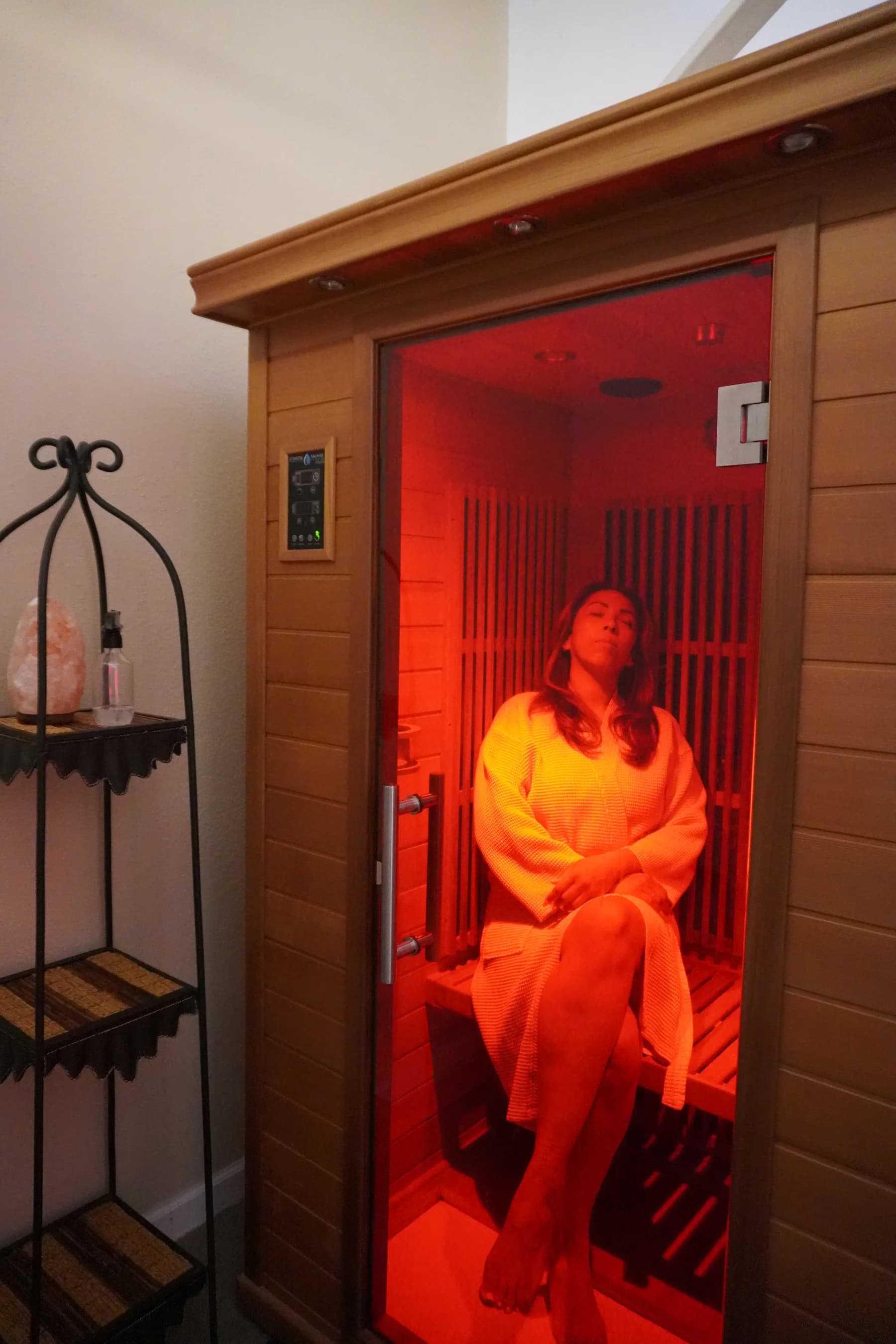 Client relaxing in an infrared sauna with warm therapeutic light.