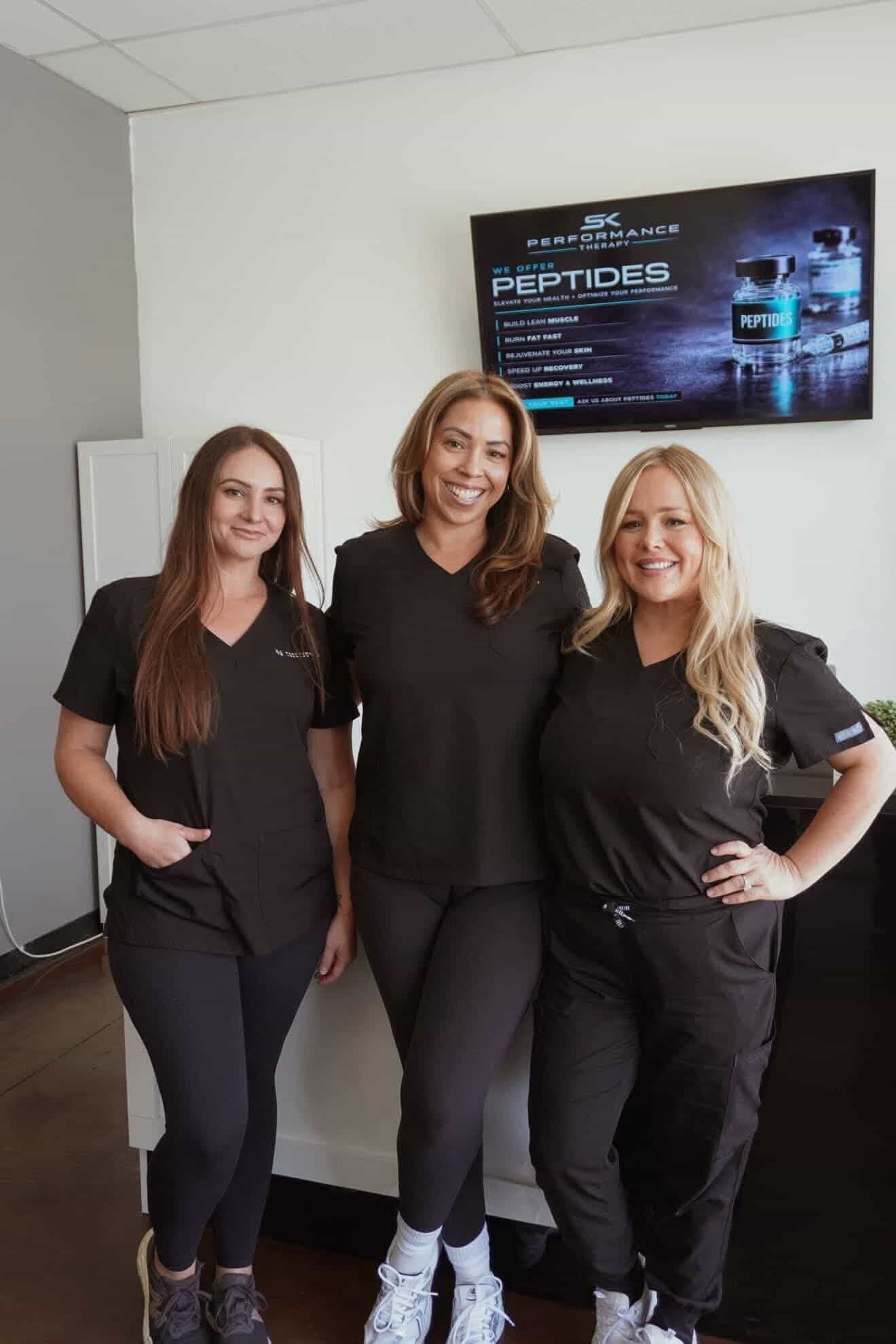 SK Longevity team members in black scrubs near a clinic screen.