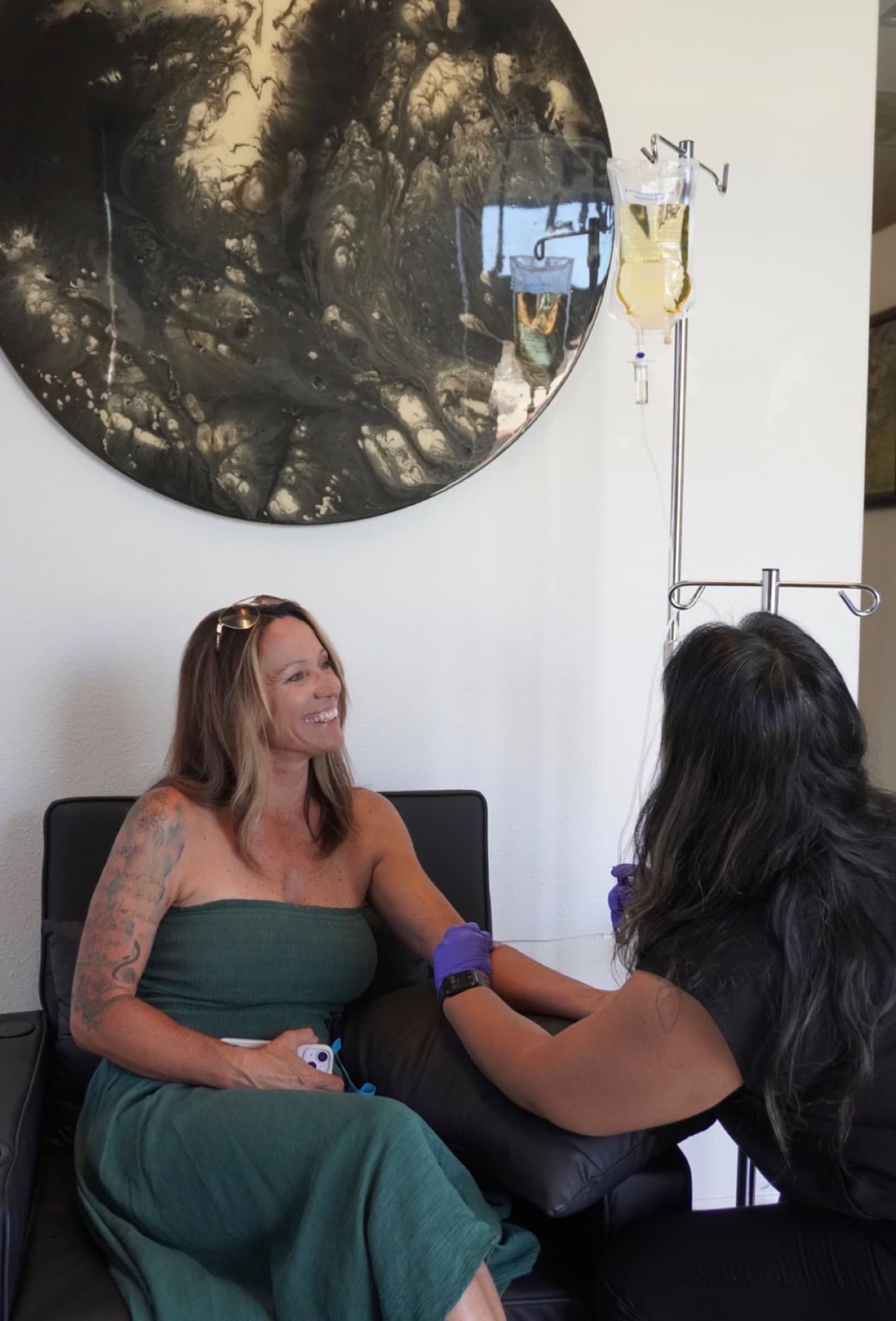 Smiling SK Longevity client receiving IV therapy in a warm wellness lounge.