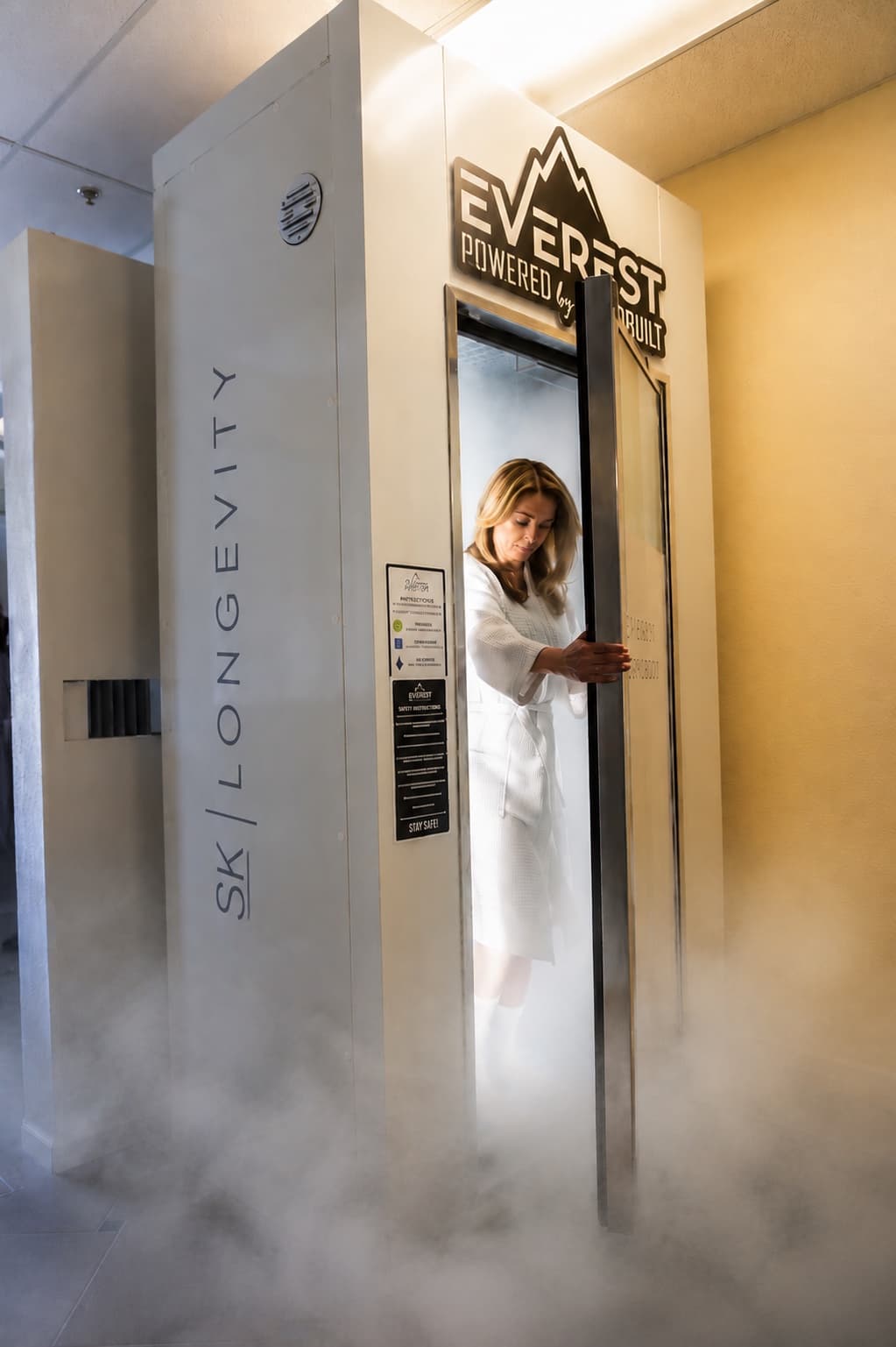 SK Longevity whole-body cryotherapy chamber with cold vapor and client stepping inside.